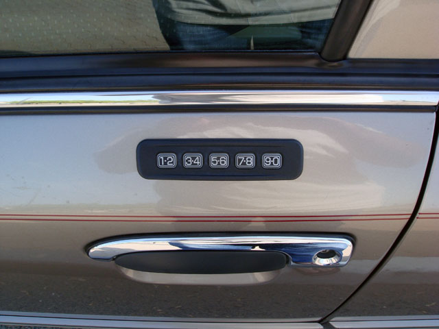 Keyless entry keypad above chrome door handle on tan car door with red pinstripe
