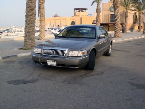 2007 Mercury Grand Marquis - 2007 Mercury Grand Marquis parked near a waterfront with boats and palm trees.