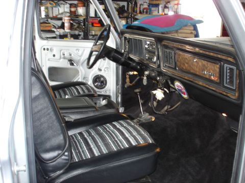 1979 Ford Bronco - The interior of a 1978 Ford Bronco is visible, striped seats and a wood-grain dashboard panel.