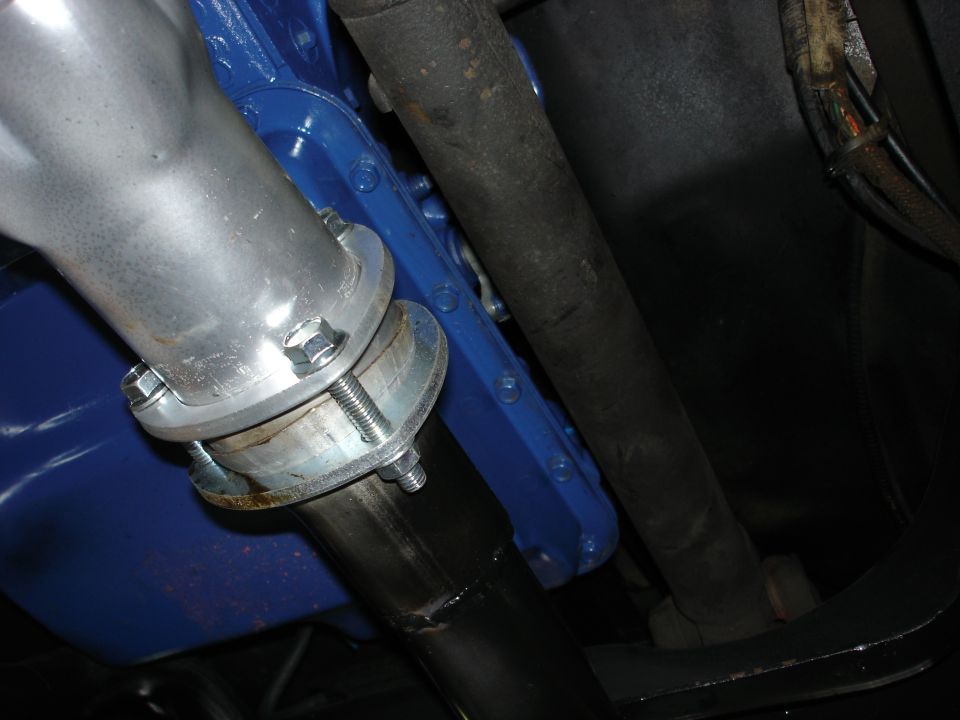 Close-up of vehicle undercarriage showing exhaust pipe connection and driveshaft