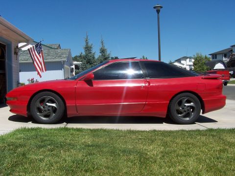 1994 Ford Probe - Side profile of a red 1994 Ford Probe coupe parked in a suburban driveway on a sunny day.