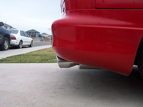1994 Ford Probe - Rear view of a red car showing its bumper and exhaust pipes, with other vehicles and houses in the background.