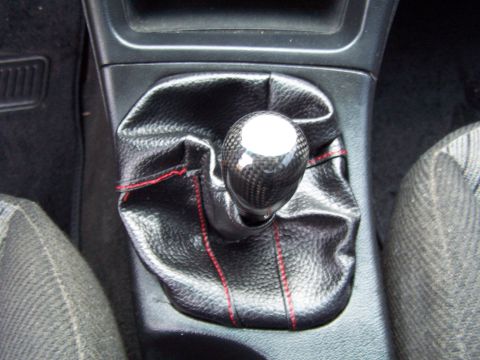 1994 Ford Probe - Close-up of a car's interior gear shifter with a carbon fiber knob and red stitching on the boot.