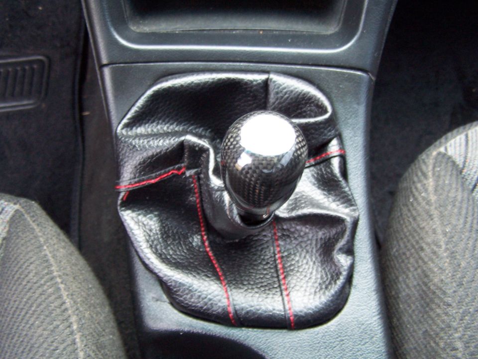 Gear shifter with carbon fiber knob and black leather boot with red stitching