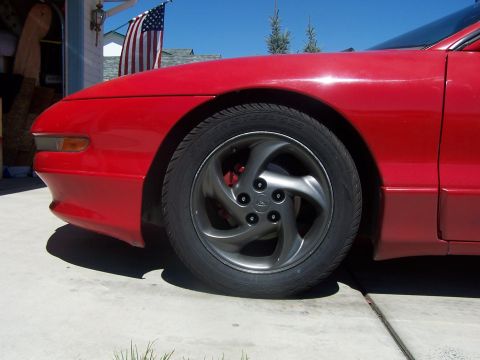 1994 Ford Probe - Close-up of the front wheel and fender of a red 1994 Ford Probe.