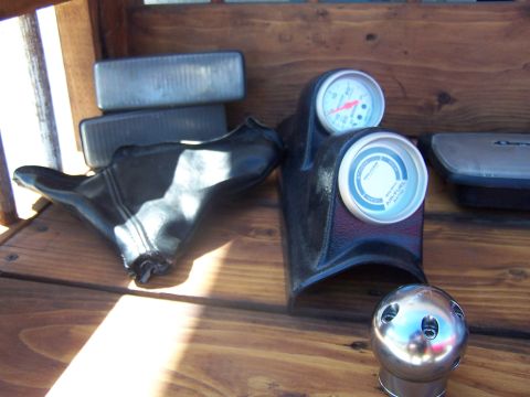 1994 Ford Probe - Various car parts are laid out on a wooden surface, including a shift boot, gauges, and a chrome shift knob.