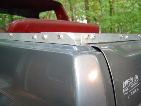 1986 Ford Bronco - Close-up of a metallic gray truck bed rail with a custom aluminum mounting bracket bolted along the top edge, likely for a bed cover or rac…