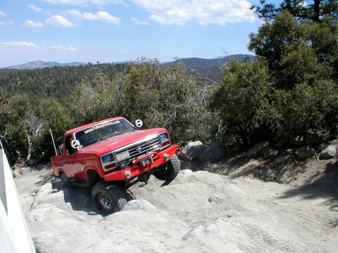 1996 Ford Bronco - Modified 1980s Ford F-Series truck tackles challenging rocky terrain on an off-road trail.