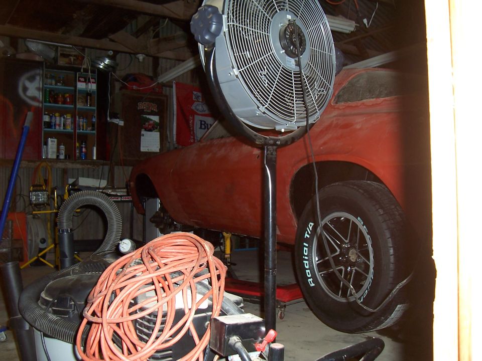 Side view of a red 1979 Chevrolet Camaro on jack stands in a garage