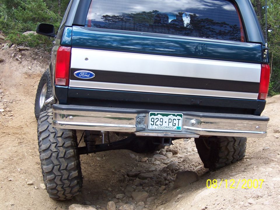 Rear of a lifted green Ford Bronco on a dirt trail with Colorado plate