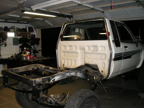 1986 Toyota Hilux - Pickup truck chassis in a garage, with the bed removed and frame exposed for modification.
