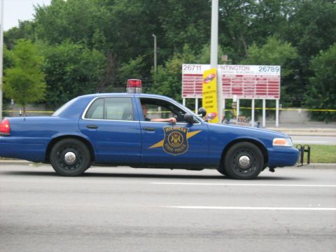 1988 Mercury Grand Marquis - A blue Michigan State Police car is seen from the side, equipped with a light bar on its roof.