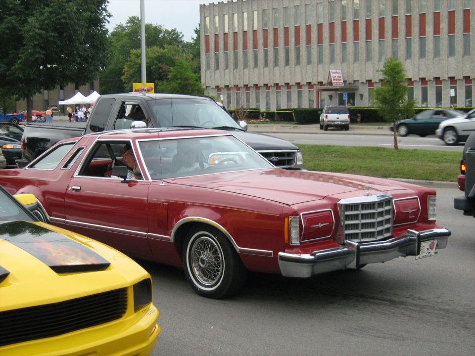 Red coupe with chrome trim and wire wheels, seen from the front-right