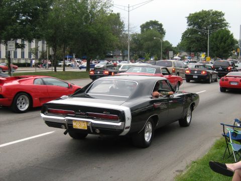 1988 Mercury Grand Marquis - A classic black Dodge Charger cruises down the road with other vehicles, including a red Lamborghini.