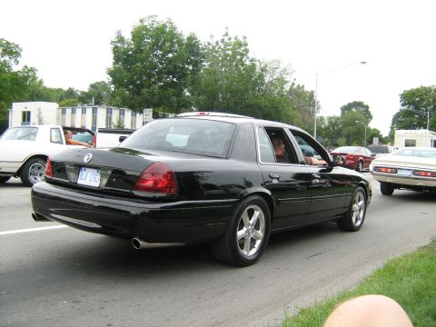 1988 Mercury Grand Marquis - Black sedan with custom wheels driving on a road during the day.
