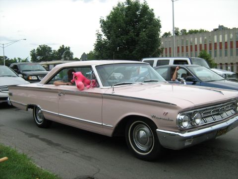 1988 Mercury Grand Marquis - A pink Mercury with a white roof is seen from the front quarter angle with a stuffed animal in the window.