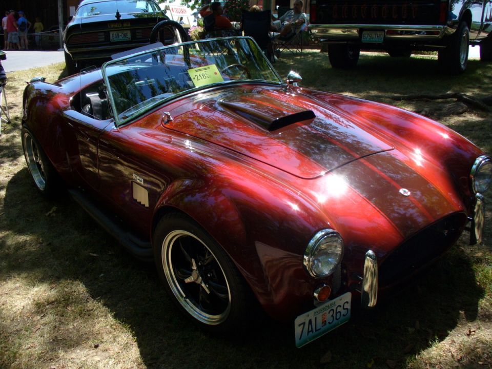 Red convertible sports car with racing stripes and scoop on hood