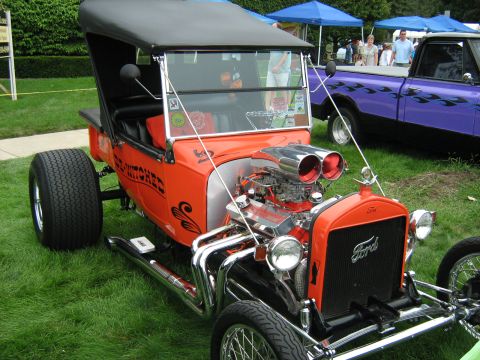 1988 Mercury Grand Marquis - A custom hot rod with a powerful engine sits on display at a car show, with other vehicles in the background.