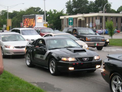 1988 Mercury Grand Marquis - A black Ford Mustang with a hood scoop and 'BOSS' decal is seen in traffic.