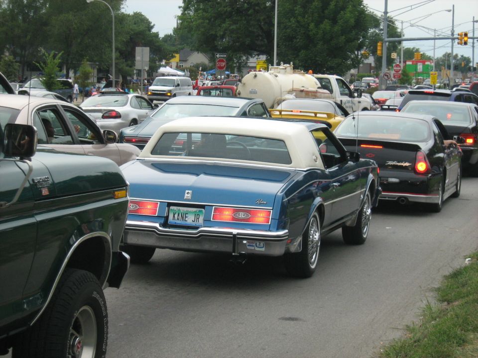 Blue coupe with white vinyl roof and 'KANE JR' license plate in traffic