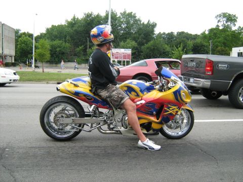 1988 Mercury Grand Marquis - A custom motorcycle with flame graphics is parked on a street next to other vehicles.