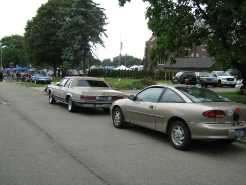 1988 Mercury Grand Marquis - Two cars are parked on a street during an outdoor event.