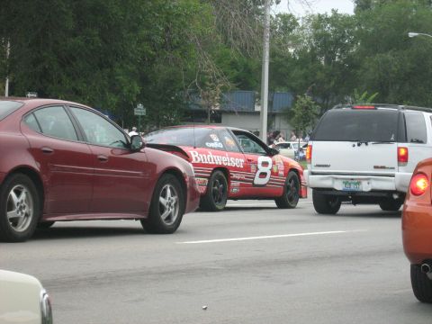 1988 Mercury Grand Marquis - A Budweiser sponsored race car is seen on the road with other vehicles.