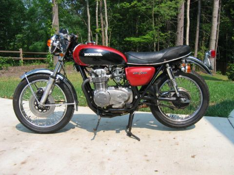 1985 Ford Crown Victoria LTD - A red and black Honda motorcycle is parked on a concrete surface with a wooded background.