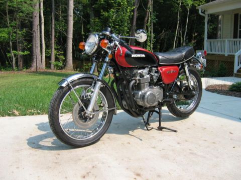 1985 Ford Crown Victoria LTD - A red and black Honda motorcycle is parked on a concrete driveway in front of a grassy area and trees.