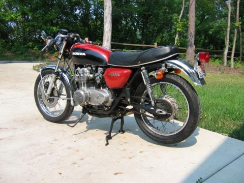 1985 Ford Crown Victoria LTD - A vintage Honda motorcycle is parked outdoors on a paved surface with a grassy area and trees in the background.
