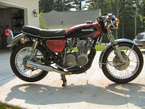 1985 Ford Crown Victoria LTD - A Honda CB500 Four motorcycle is parked outside a garage.