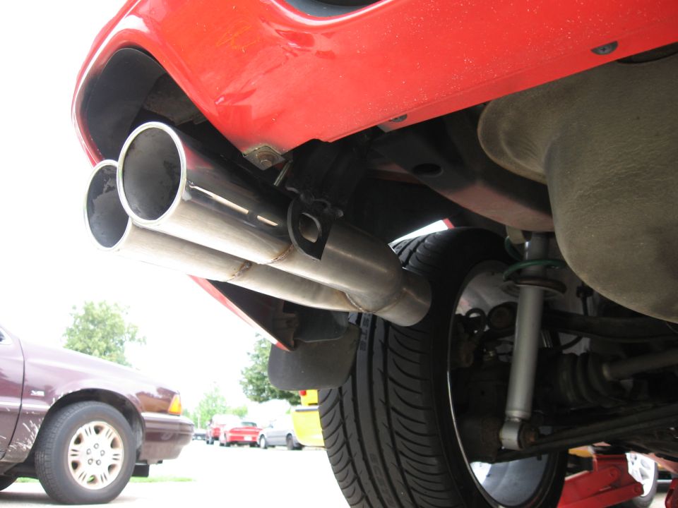 Dual chrome exhaust pipes on a red car's rear bumper