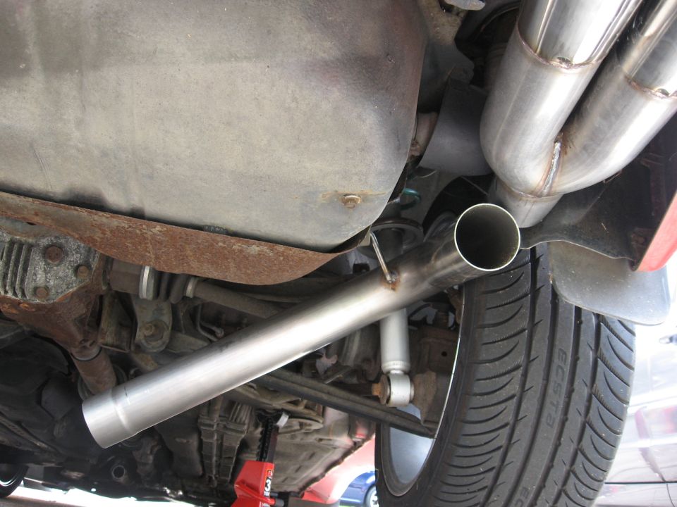 Underside of a vehicle showing a dual exhaust pipe, suspension components, and a differential