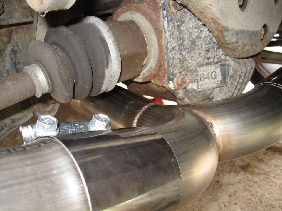 Close-up of a shiny exhaust pipe and drive axle with a B4G label