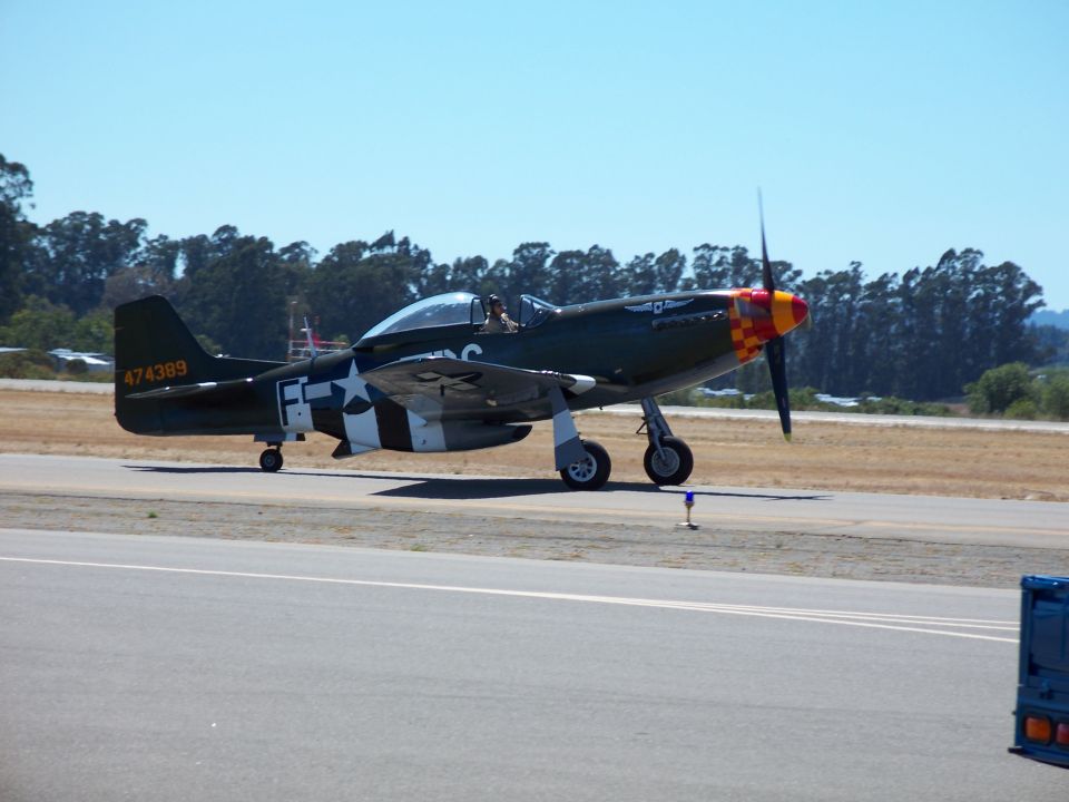 Green airplane with white star insignia and orange/yellow checkered nose art on a runway