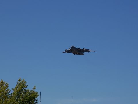 1990 Ford Bronco - A large cargo plane is seen flying in the sky with trees in the foreground.