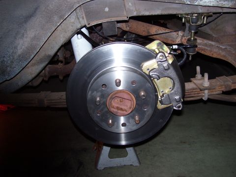 1968 Ford Mustang - The rear brake assembly of a vehicle is shown, with the rotor and caliper prominently displayed.