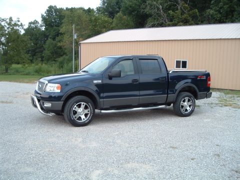 2005 Ford F-150 - This pickup truck has a chrome bull bar and running boards, parked on a gravel lot.