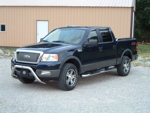 2005 Ford F-150 - This pickup truck has a chrome grille guard and side steps, parked on a gravel lot.