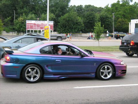 1988 Mercury Grand Marquis - A customized Ford Mustang with a unique iridescent paint job drives down the road.