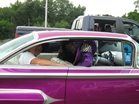 1988 Mercury Grand Marquis - Interior view of a vibrant purple custom car with people inside, a pickup truck is visible in the background.