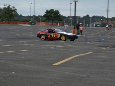 2001 Mercury Grand Marquis - A red and white sports car with racing decals is seen on a paved lot with cones.