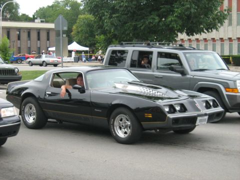 1988 Mercury Grand Marquis - Black late-1970s Pontiac Firebird coupe with gold pinstriping, a checkered-flag decal hood scoop and polished five-spoke wheels on Mickey T…