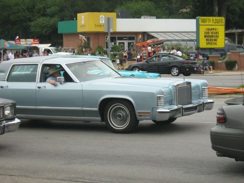 1988 Mercury Grand Marquis - A light blue 1977 Lincoln Continental sedan is seen from the side, with other vehicles in the background.