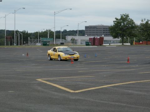 2001 Mercury Grand Marquis - A yellow Ford Mustang navigates a course marked by cones in an empty parking lot.
