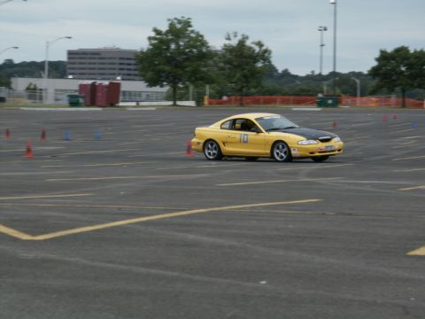 2001 Mercury Grand Marquis - A yellow coupe with a black hood navigates a cone course on an overcast day.