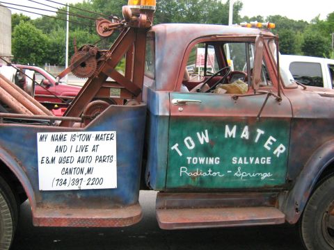 1988 Mercury Grand Marquis - This tow truck, nicknamed "Tow Mater," is seen with "TOWING SALVAGE" painted on its side and a sign with contact information.