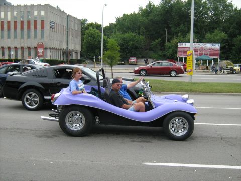 1988 Mercury Grand Marquis - A purple dune buggy with two occupants drives alongside other vehicles on a sunny day.