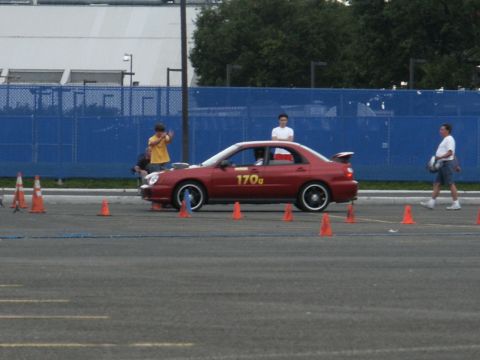 2001 Mercury Grand Marquis - A red sedan with a spoiler and racing numbers is positioned on a track with orange cones.