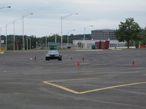 2001 Mercury Grand Marquis - A black sedan drives through a parking lot marked with cones, suggesting a driving event or course.